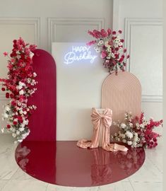 a red table topped with pink and white flowers next to a sign that says happy birthday