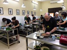 a group of people in a kitchen preparing food on top of metal tables and pans