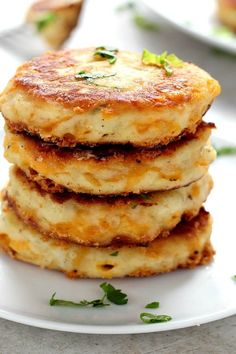 a stack of food sitting on top of a white plate covered in cheese and parsley