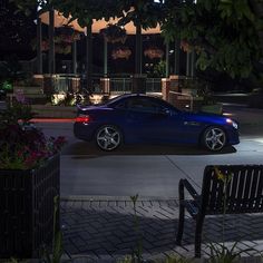 a blue sports car parked in front of a building at night with its lights on