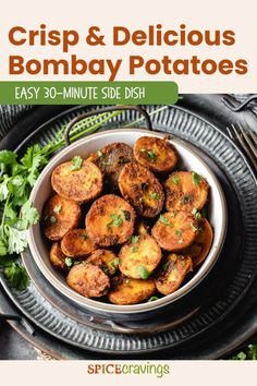 a bowl filled with fried potatoes on top of a black plate next to cilantro