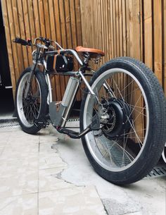 a motorcycle parked in front of a wooden wall next to a bike tire on the ground