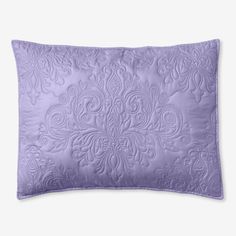 a purple pillow with an intricate design on the front and back, sitting on a white surface