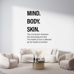 a living room with white furniture and a quote on the wall that says mind, body, skin