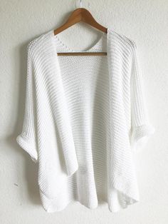 a white sweater hanging on a wooden hanger