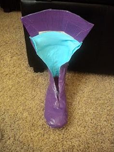 a purple vase sitting on top of a carpeted floor next to a black box