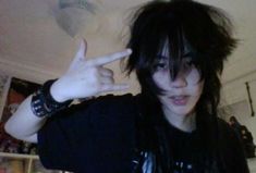 a man with long black hair giving the peace sign