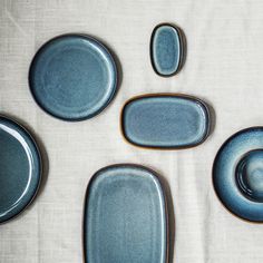 four blue plates and two cups on a white tablecloth