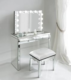 a vanity with a stool and lighted mirror