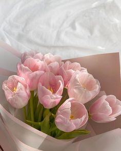 a bouquet of pink tulips sitting on top of a bed