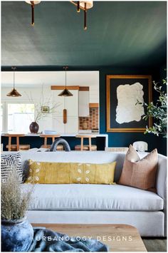 a living room with blue walls and white couches, wooden tables and chairs in the background