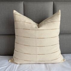 a white pillow sitting on top of a bed next to a gray headboard and pillows