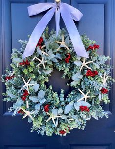 a wreath with starfishs, holly and berries hangs on a blue door frame