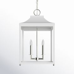 a white lantern hanging from a chain on a wall with two candles in the middle