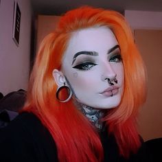 a woman with orange hair and piercings on her face