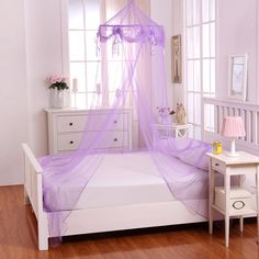 a white bed with a purple mosquito net on it's headboard and foot board