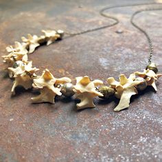 a necklace with flowers on it is sitting on a stone surface in front of a brick wall