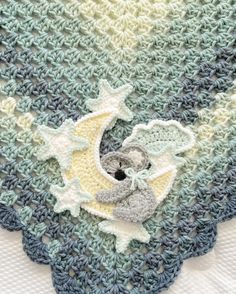 a crocheted blanket with a teddy bear on the moon and stars in it