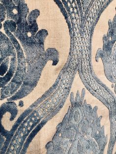 an old blue and white wallpaper with ornate designs on the fabric, close up