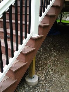 a wooden stair case next to a white hand rail