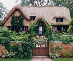 an old brick house with ivy growing on it's roof and door, surrounded by greenery