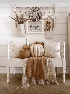 a white bench topped with lots of pillows and stuffed animals next to a sign that says happy pumpkin