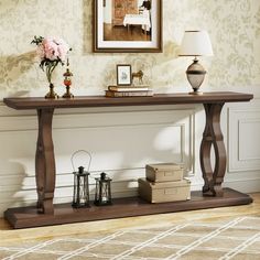 a wooden table sitting on top of a hard wood floor next to a lamp and pictures