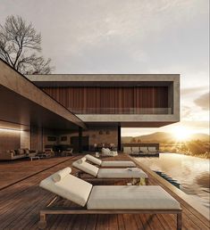 the sun is setting over an outdoor pool and deck area with chaise lounges