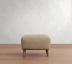 a small footstool sitting on top of a wooden floor next to a wall