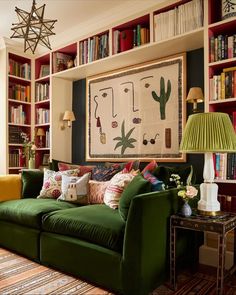 a living room filled with green couches and lots of books on the shelves behind them