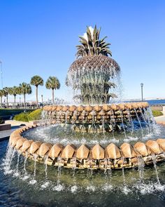 a water fountain with pineapples on top and palm trees in the background