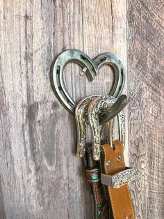 an old pair of scissors hanging from a hook on a wooden wall with heart shaped handles