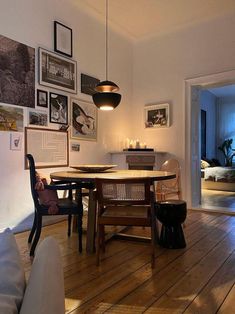 a dining room table with chairs and pictures on the wall above it in an apartment