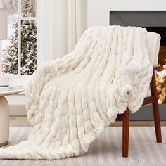 a white blanket sitting on top of a wooden chair in front of a fire place