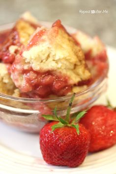 strawberry cobbler in a bowl with two strawberries on the side