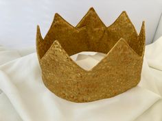 An adjustable crown made with Gold cotton metallic fabric. This crown is comfortably padded and easily washable.  Good for singling out the birthday person or celebrating the upcoming coronation.  Easily applied with Velcro Adjustable Tall Gold Crown, Adjustable Gold Crown For Party, Gold Birthday Crown With Tall Shape, Gold Tall Crown For Birthday, Gold Adjustable Crown For Party, Royal Gold Party Crown, Royal Gold Crown For Parties, Royal Gold Crown With Pinched Shape, Royal Gold Crown With Tall Shape