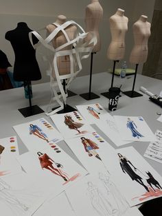 several mannequins and paper work on a table