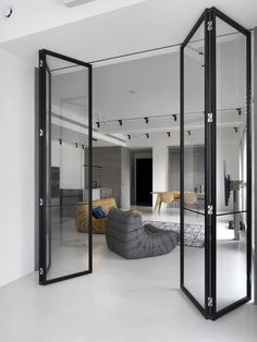 an open living room and dining area with mirrored doors on the walls, white flooring and black furniture