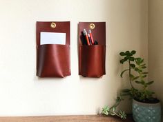 Warm brown leather wall pockets hang above a table and potted plant. Hanging Pencil Holder, Home Command Center, Spice Holder, Leather Organizer, English Bridle, Leather Organization, Leather Wall, Earthy Scent, Command Center