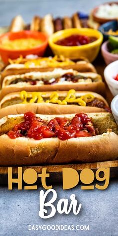 hot dogs with ketchup and mustard are lined up on a long wooden board