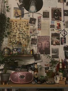 a room with various plants and pictures on the wall, including an old record player