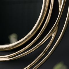 a close up of a mirror on a wall with some gold colored metal rings around it