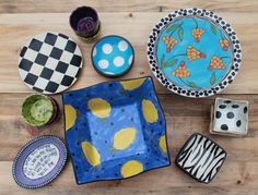 several plates and bowls are arranged on a wooden table with dices in the middle