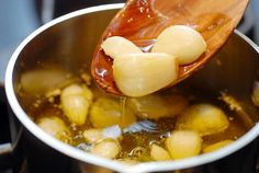 a wooden spoon is being used to stir food in a pot filled with potatoes and broth