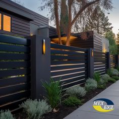 a modern home with black fence and landscaping