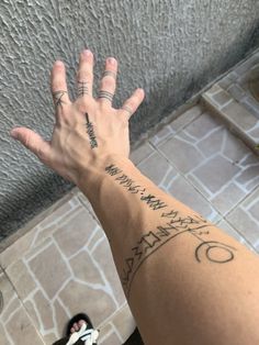 a person's arm with tattoos on it and one hand up to the ceiling