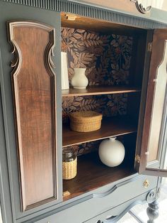 a cabinet with some vases in it and other items on the shelf behind it