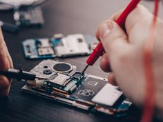 a man is working on an electronic device with a red pen and screwdriver