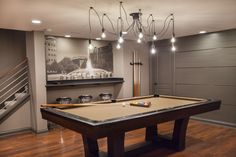 a pool table in the middle of a room with lights hanging from it's ceiling