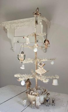 a white christmas tree sitting on top of a table next to a shelf filled with ornaments